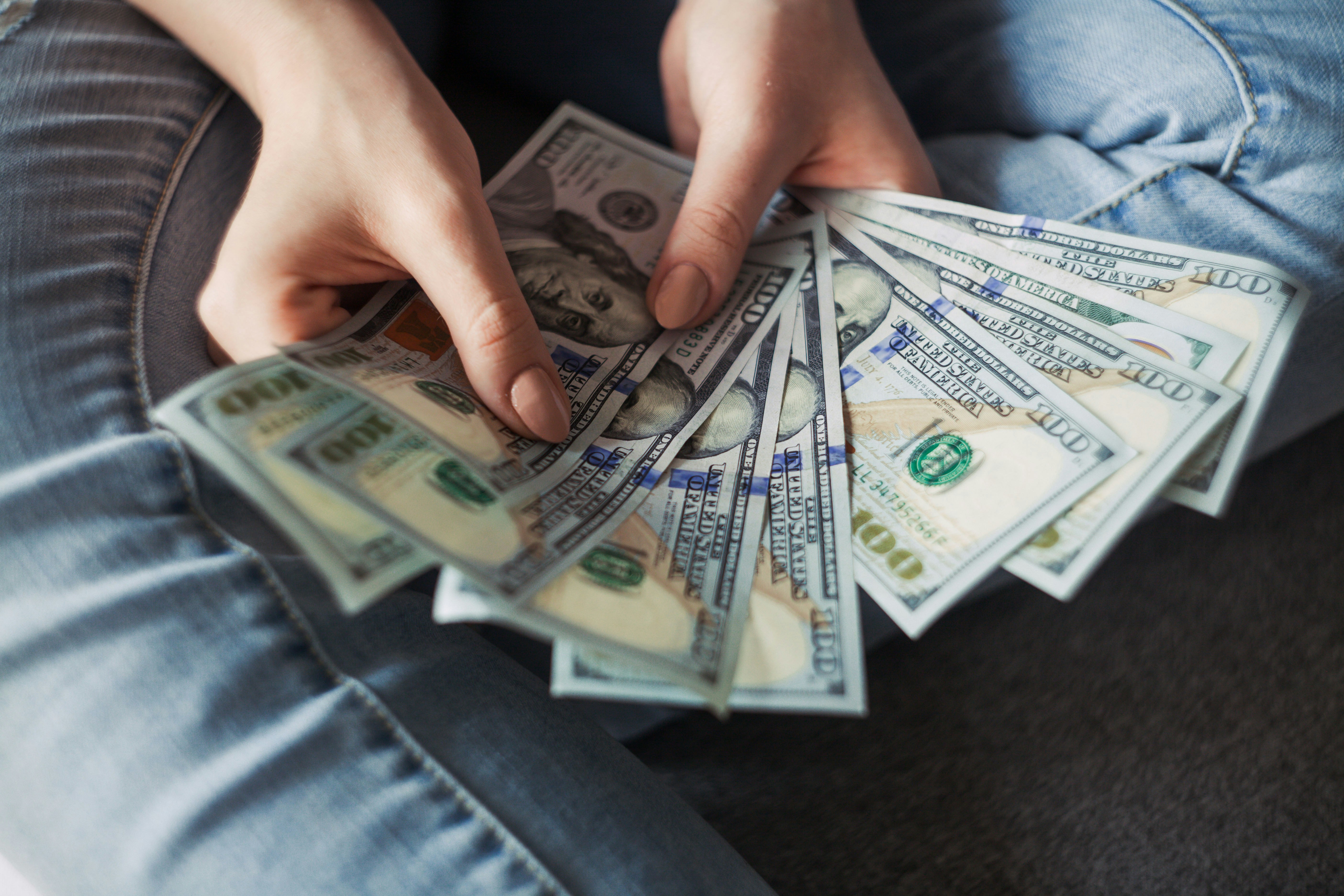 Hands holding a fan of one hundred dollar bills